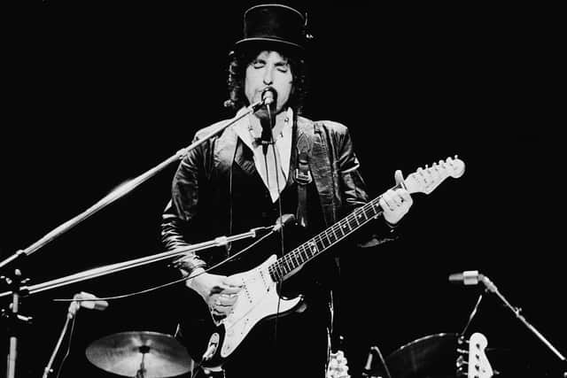 American singer and songwriter Bob Dylan sings and plays guitar on stage, wearing a top hat, during the Blackbushe Pop Festival, Hampshire, England, July 17, 1978. (Photo by Express Newspapers/Getty Images)