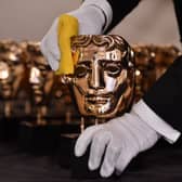 A member of staff polishes BAFTA award winners masks. (Photo credit should read BEN STANSALL/AFP via Getty Images)