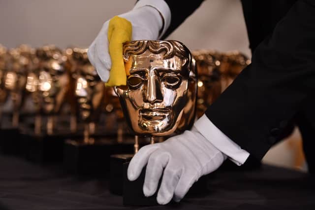 A member of staff polishes BAFTA award winners masks. (Photo credit should read BEN STANSALL/AFP via Getty Images)