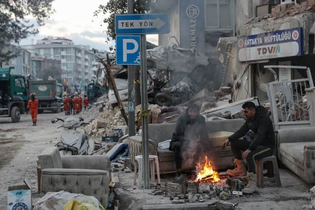 People sit in front of collapsed buildings in Hatay, Turkey (Photo: Burak Kara/Getty Images)
