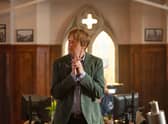 Kris Marshall as Humphrey Goodman in Beyond Paradise, stood in the Shipton Abbott police station with his hands steepled (Credit: Red Planet Pictures)