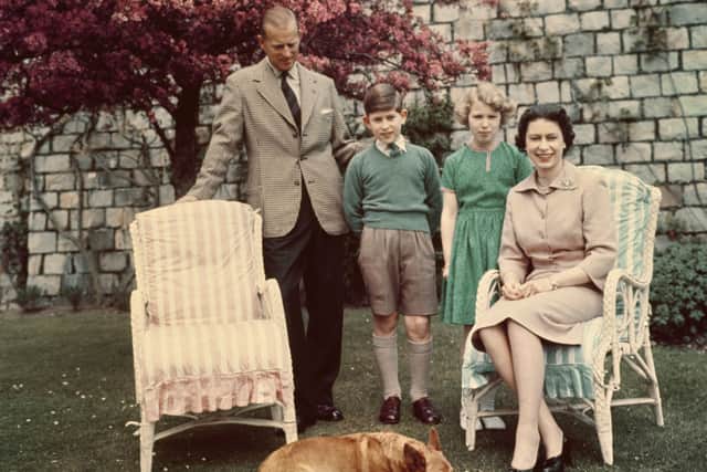 British Royals Prince Philip, Duke of Edinburgh (1921-2021), Prince Charles of Edinburgh. Princess Anne of Edinburgh, and Queen Elizabeth II (1926-2022), who sits in a wicker garden chair with her corgi Sugar asleep at her feet, in the gardens below the East Terrace on the South Front of Windsor Castle in Windsor, Berkshire, England, June 1959. (Photo by Keystone/Hulton Archive/Getty Images)