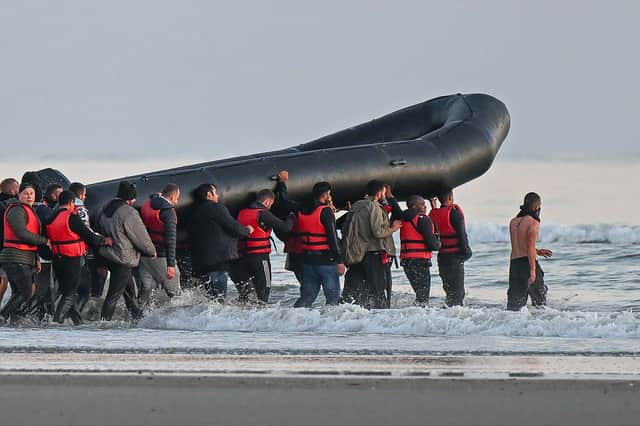 About 40 migrants hold an inflatable boat before boarding to attempt crossing the Channel to Britain, near the northern French city of Gravelines on July 11, 2022 (Image: DENIS CHARLET/AFP via Getty Images)