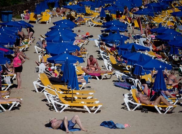 Tourists lay on rows of sun umbrellas on Playa Blaca beach in Lanzarote (Image: Getty)