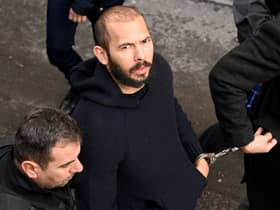 British-US influencer Andrew Tate arrives handcuffed and escorted by police at a courthouse in Bucharest on February 1, 2023 (Photo by DANIEL MIHAILESCU/AFP via Getty Images)