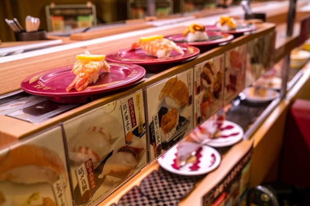 This picture shows plates of sushi on a conveyor belt at a sushi chain restaurant in Tokyo on February 3, 2023. Credit: Getty Images
