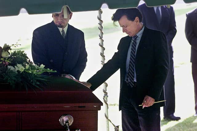 Actor Robert Blake places a hand on the coffin bearing his slain wife, Bonny Lee Bakley, during a brief funeral ceremony May 25, 2001 in Los Angeles, California (Pool Photo/Getty Images)