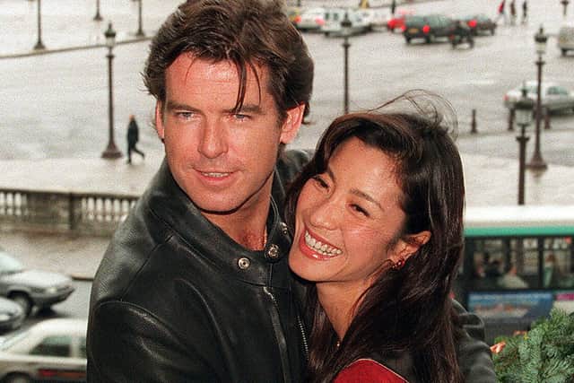 December 11, 1997: Pierce Brosnan and Michelle Yeoh pose on the balcony of the prestigious Paris Crillon hotel next to the Place de la Concorde in Paris (Photo by THOMAS COEX/AFP/GettyImages)