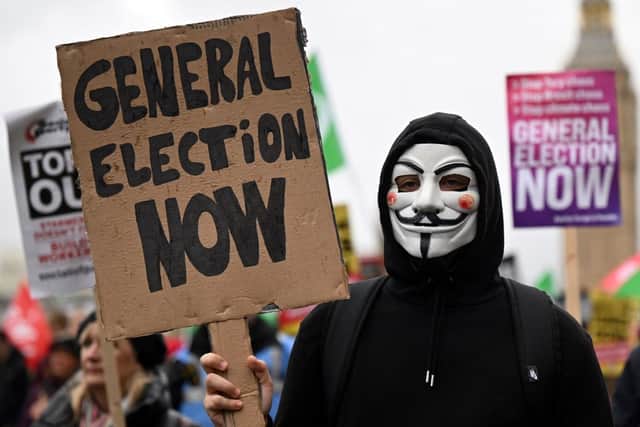 Demonstrators with placards calling for a General Election march near the Houses of Parliament in 2022 (Photo: JUSTIN TALLIS/AFP via Getty Images)