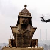A US military helicopter hovers over a giant bronze bust of Saddam Hussein as workers prepare to dismantle it at the former presidential palace in Baghdad 02 December 2003 (Photo: PETER KUJUNDZIC/AFP via Getty Images)
