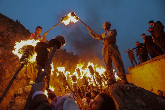 Iraqi Kurds holding lit torches walk up a mountain during a procession to celebrate their Nowruz New Year festival in Akre, the country’s northern autonomous Kurdish region, on March 20, 2023 (Photo by SAFIN HAMED/AFP via Getty Images)