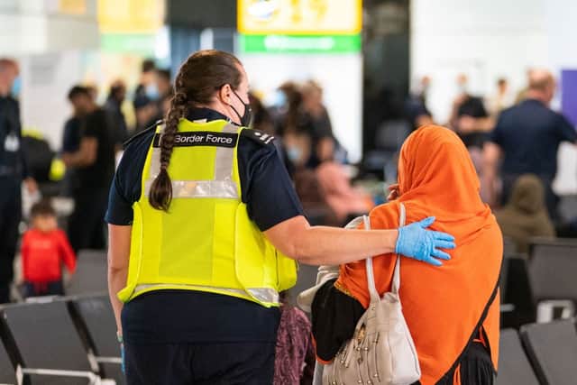 A member of Border Force staff assists an Afghan refugee on her arrival at Heathrow Airport, London, following an evacuation flight from Afghanistan on August 26, 2021. Credit: Getty Images