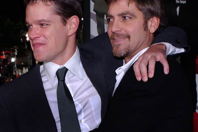 US actors George Clooney (R) and Matt Damon hug as they meet at the premiere of their new film "Oceans 11," in Los Angeles, CA, 05 December 2001.   (Credit: LUCY NICHOLSON/AFP via Getty Images)