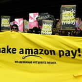 Protesters hold banners and placards during a past demonstration asking the online retailer Amazon to pay its employees fairly (Photo: MAURIZIO GAMBARINI/DPA/AFP via Getty Images)