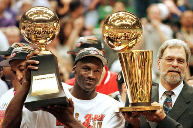 Michael Jordan holds the NBA Finals Most Valuable Player trophy and former Chicago Bulls head coach Phil Jackson holds the NBA champions Larry O’Brian trophy. (Getty Images)