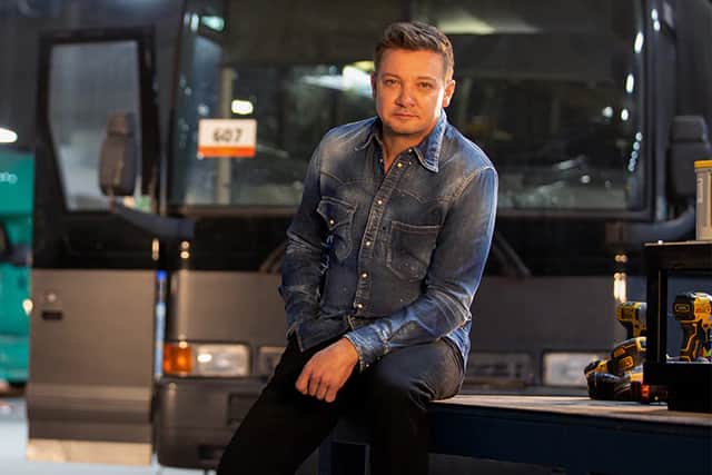 Jeremy Renner on set of Rennervations, a bus behind him and some power tools to one side (Credit: Disney+)