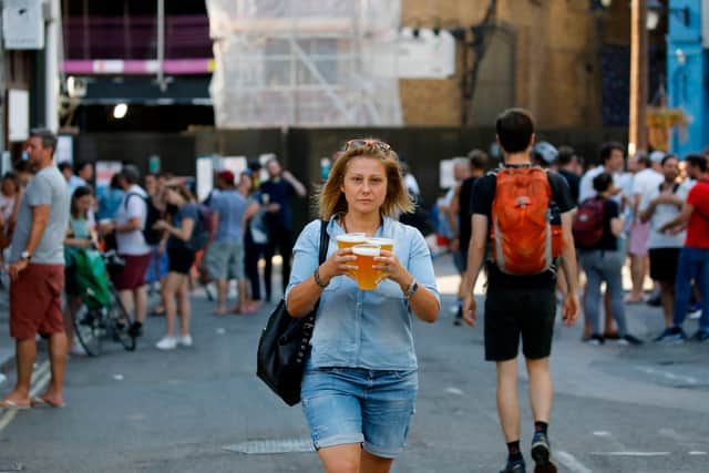 Woman carries three beers on a warm day. (Photo by TOLGA AKMEN/AFP via Getty Images)