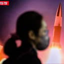 A woman walks past a television showing a news broadcast with file footage of a North Korean missile test. Picture: ANTHONY WALLACE/AFP via Getty Images