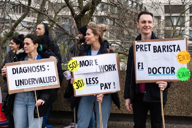 Demonstrators hold placards as they take part in a protest by junior doctors, amid a dispute with the government over pay, outside of Saint Thomas Hospital, in London, on March 13, 2023. (Photo by Niklas HALLE'N / AFP)