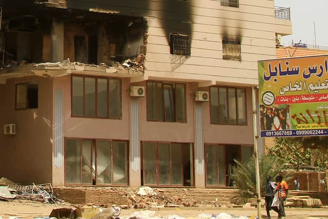 Men walk past a building damaged during battles between the forces of two rival Sudanese generals in the southern part of Khartoum. Picture: AFP via Getty Images
