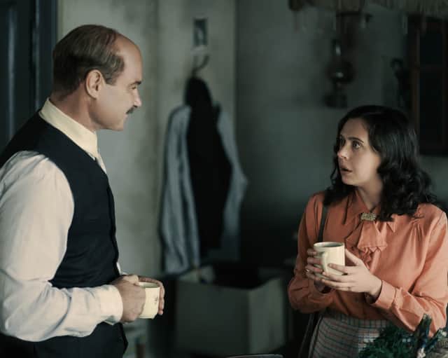 Liev Schreiber as Otto Frank and Bel Powley as Miep Gies in A Small Light, speaking to one another in the annex (Credit: National Geographic for Disney/Martin Mlaka)