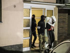 Police guide an arrested person out of a house in western Germany, as part of the "wide-scale" operation against the notorious Italian 'Ndrangheta mafia across Europe (Photo by ALEX TALASH/AFP via Getty Images)