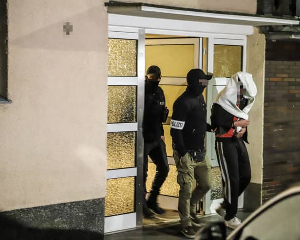 Police guide an arrested person out of a house in western Germany, as part of the "wide-scale" operation against the notorious Italian 'Ndrangheta mafia across Europe (Photo by ALEX TALASH/AFP via Getty Images)
