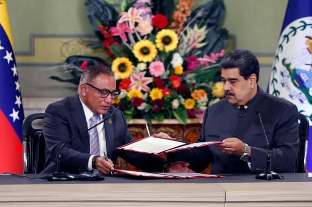 Prime Minister of Belize, Johnny Briceño (L) and Venezuelan President Nicolás Maduro (R)  exchange documents during a meeting at Miraflores presidential palace in Caracas, on November 25, 2022. (Photo by PEDRO RANCES MATTEY/AFP via Getty Images)