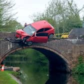 Car left dangling precariously off a bridge after a crash. Picture: Stephanie Hardman / SWNS