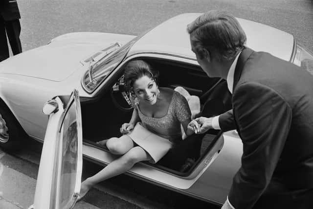 English actress, author and columnist Joan Collins stepping out of a car with the help of American actor George Peppard (1928 - 1994) during filming of 'The Executioner', UK, 9th May 1969. (Photo by David Cairns/Daily Express/Hulton Archive/Getty Images)