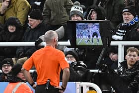 Referee Paul Tierney makes a VAR check in front of Newcastle fans