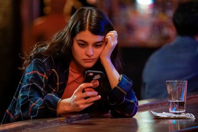 Sofia Black-D'Elia as Sam in Single Drunk Female, checking her phone at the bar (Credit: Freeform/Disney+/Elizabeth Sisson)