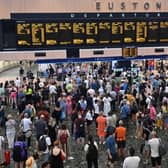 Rail passengers wait to board trains at Euston station in London (Photo by JUSTIN TALLIS/AFP via Getty Images)