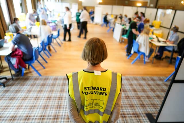 A steward volunteer watches over patients as they receive their Pfizer-BioNTech COVID-19 vaccines at the Hexham Mart Vaccination Centre on May 13, 2021 in Hexham, England.