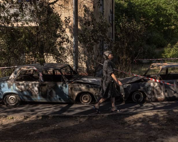 A woman walks next to burned cars at the site where Russia's intercepted drone debris fell, on May 31, 2023 