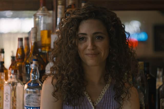 Emmy Rossum as Candy in The Crowded Room, a shelf of drinks behind her (Credit: Apple TV+)