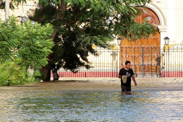 Residents in the city of Piura, 1,000 kilometres north of Lima, wade through water on the streets on March 27, 2017, after nearly 15 hours of rain caused the Piura River to overflow, flooding neighbourhoods in most of the city. - The El Nino climate phenomenon is causing muddy flash floods and rivers to overflow along the entire Peruvian coast. (Photo by PATRICIA LACHIRA/AFP via Getty Images)