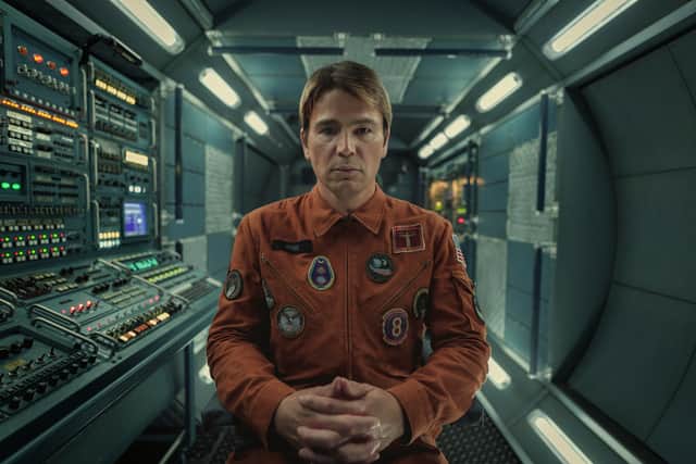 Josh Hartnett as David Ross in Black Mirror 6x3 Beyond the Sea, wearing an orange jumpsuit and sitting in a spaceship, surrounded by switches and dials (Credit: Nick Wall/Netflix)