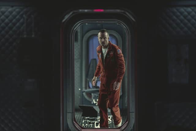 Aaron Paul as Cliff Stanfield in Black Mirror Season 6 episode 3 'Beyond the Sea', stood in a doorway wearing an orange boilersuit (Credit: Nick Wall/Netflix)