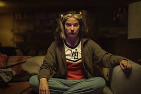 Annie Murphy as Joan in Black Mirror Season 6 episode 1 'Joan is Awful', cross legged on the sofa (Credit: Nick Wall/Netflix)