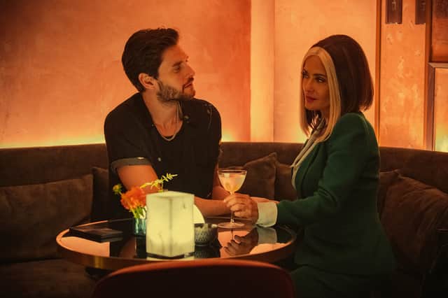 Ben Barnes as TV Mac and Salma Hayek-Pinault as Salma Hayek-Pinault as TV Joan in Black Mirror Season 6 episode 1 'Joan is Awful', eating dinner together at a dimly lit table (Credit: Ana Blumekron/Netflix)