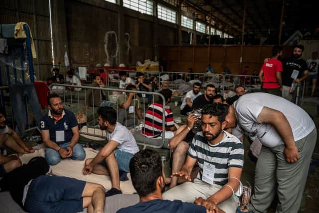 Survivors wait inside a warehouse in Kalamata, after a boat carrying migrants sank in international waters (Photo by ANGELOS TZORTZINIS/POOL/AFP via Getty Images)
