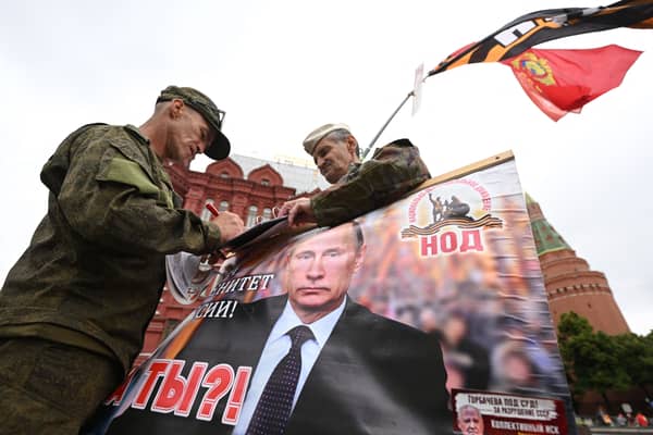 Activists hold a portrait of Russian President Vladimir Putin near Red Square in Moscow (Photo: NATALIA KOLESNIKOVA/AFP via Getty Images)