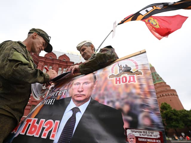 Activists hold a portrait of Russian President Vladimir Putin near Red Square in Moscow (Photo: NATALIA KOLESNIKOVA/AFP via Getty Images)