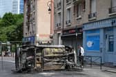 A pedestrian looks at an overturned burnt car in the street in Puteaux, west of Paris on June 30, 2023. Picture:  BERTRAND GUAY/AFP via Getty Images