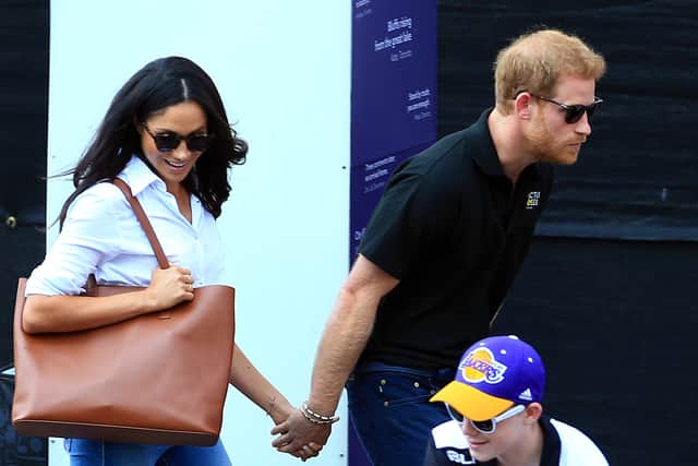 Prince Harry (R) and Meghan Markle (L) hold hands a Wheelchair Tennis match during the Invictus Games 2017 at Nathan Philips Square on September 25, 2017 in Toronto, Canada.  (Photo by Vaughn Ridley/Getty Images for the Invictus Games Foundation)