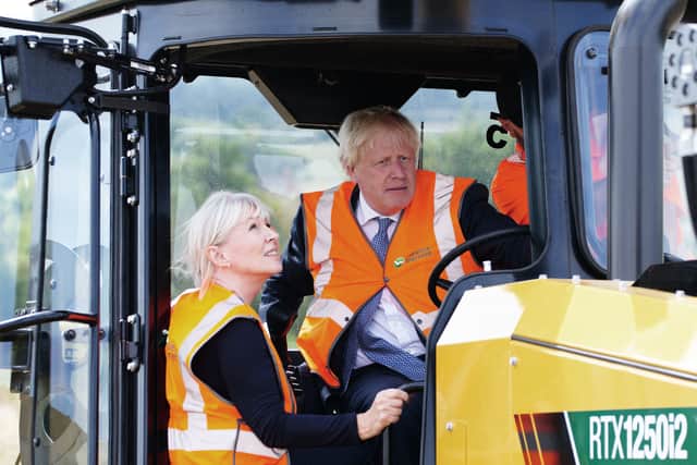 Britain's Prime Minister Boris Johnson (R) and Britain's Culture Secretary Nadine Dorries (L) sit in mole plough during a visit of the Henbury Farm in north Dorset, on August 30, 2022. (Photo by BEN BIRCHALL/POOL/AFP via Getty Images)