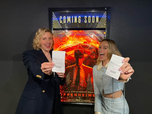 Barbie director Greta Gerwig and star Margot Robbie pose in front of the Oppenheimer poster 