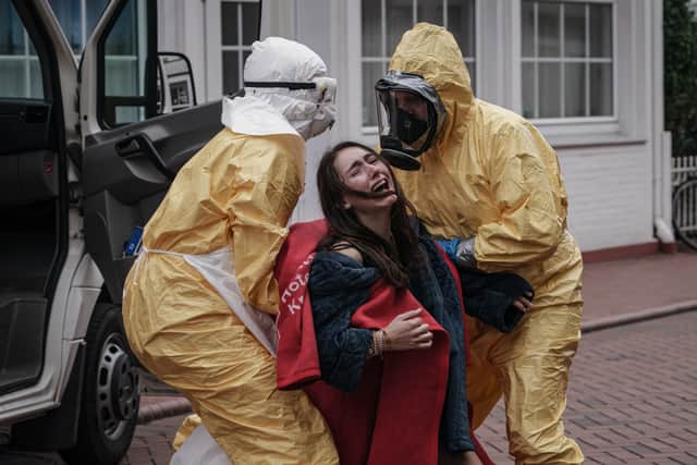 Two men in yellow hazmat suits drag an infected woman into their van in Sløborn (Credit: Stefan Erhard/Walter Presents)