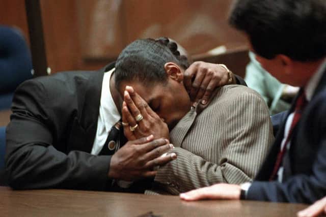 Rapper Snoop Doggy Dogg (C), whose real name is Clavin Broadus, holds his head after hearing the not-guilty verdict 20 February on first and second-degree murder charges in the shooting death of a gang member.